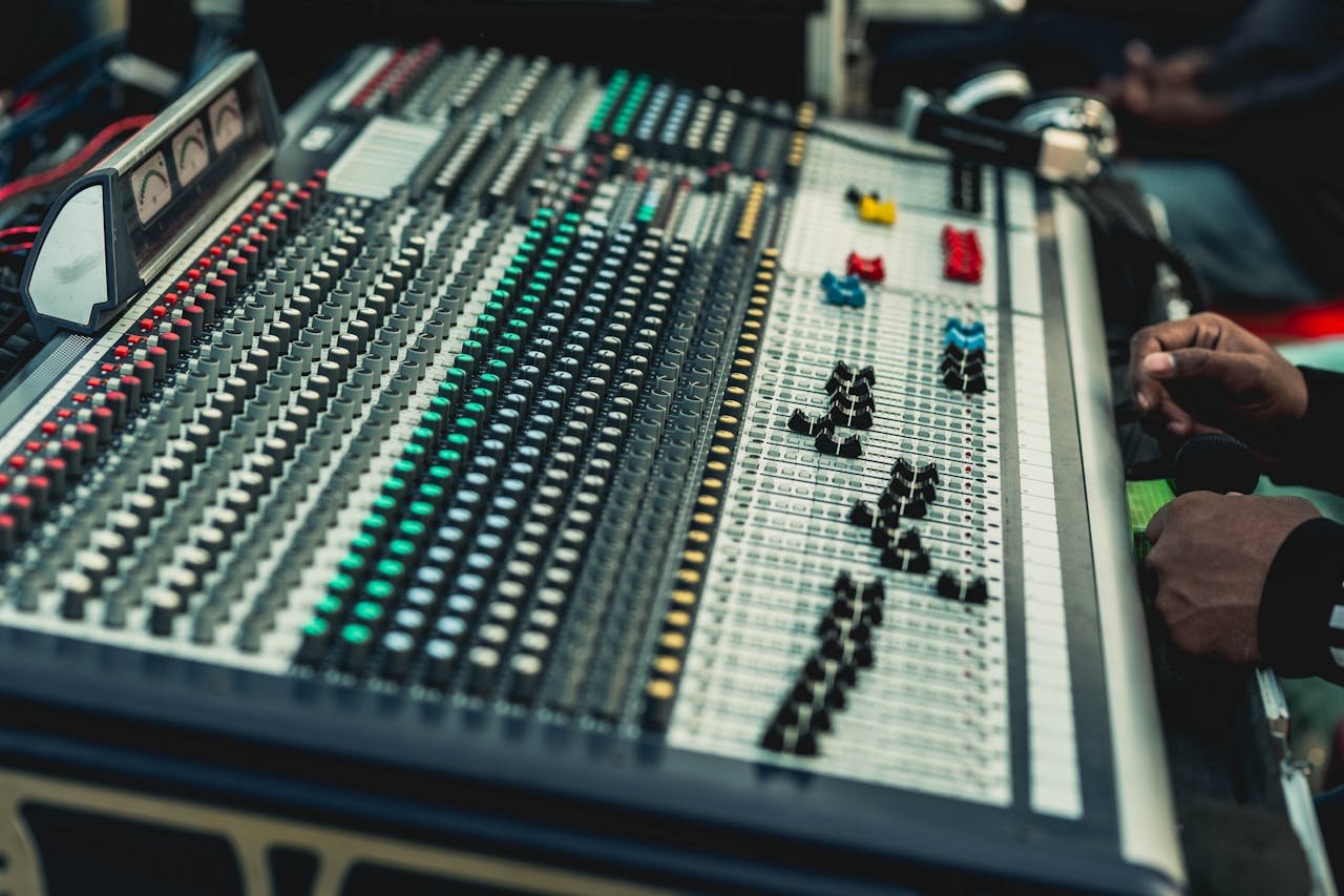 About A close-up view of a professional audio mixing console in use by a sound engineer.